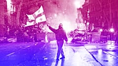 A man waves a Georgian national flag in front of a burning barricade as other protesters stand behind not far from the Georgian parliament building in Tbilisi, 9 March 2023