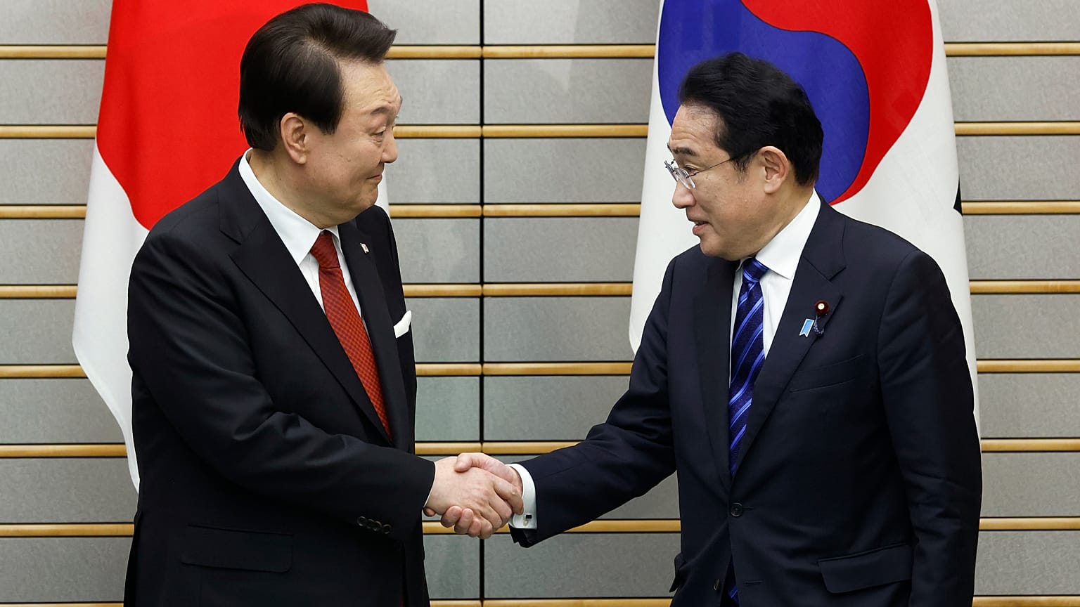South Korean President Yoon Suk Yeol and Japanese Prime Minister Fumio Kishida shake hands