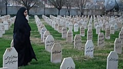 A woman passes by graves in Iraq.
