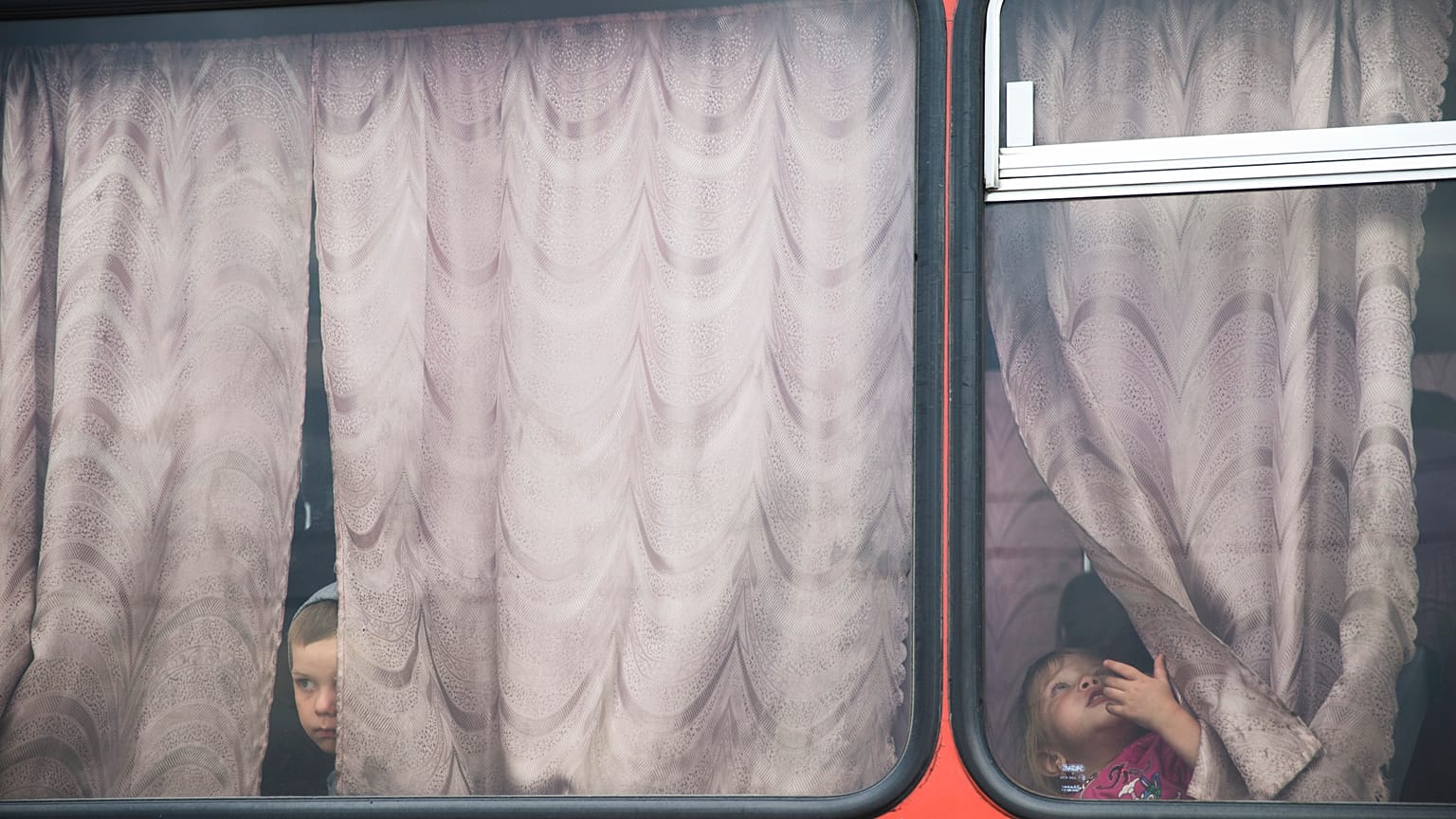Crianças dentro de um autocarro antes de partirem para um campo de refugiados