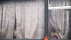 Children look out from a bus before leaving for a train station at a refugee camp set up by the Russian Emergencies Ministry about 10km from the Russia-Ukrainian border.