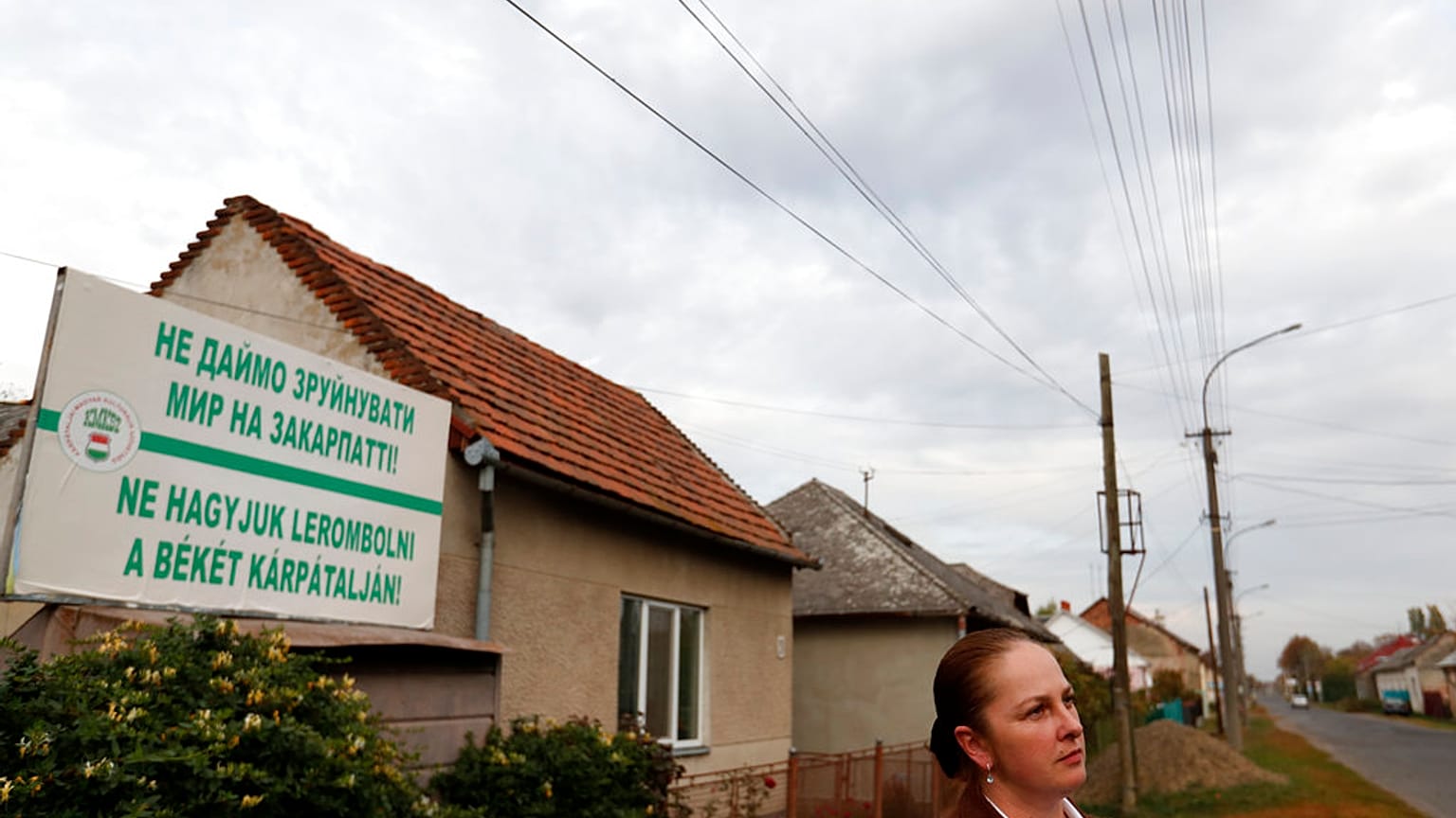 Przedstawicielka Zakarpackiego Węgierskiego Towarzystwa Kulturalnego, stoi przed billboardem z napisem „Nie pozwólmy, aby pokój na Zakarpaciu został zniszczony!”
