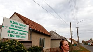 Przedstawicielka Zakarpackiego Węgierskiego Towarzystwa Kulturalnego, stoi przed billboardem z napisem „Nie pozwólmy, aby pokój na Zakarpaciu został zniszczony!”