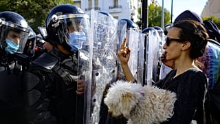 تونسية تحمل كلبا تشير بإصبعها الأوسط لرجال الشرطة أمام وزارة الداخلية بالعاصمة تونس 30/01/2021