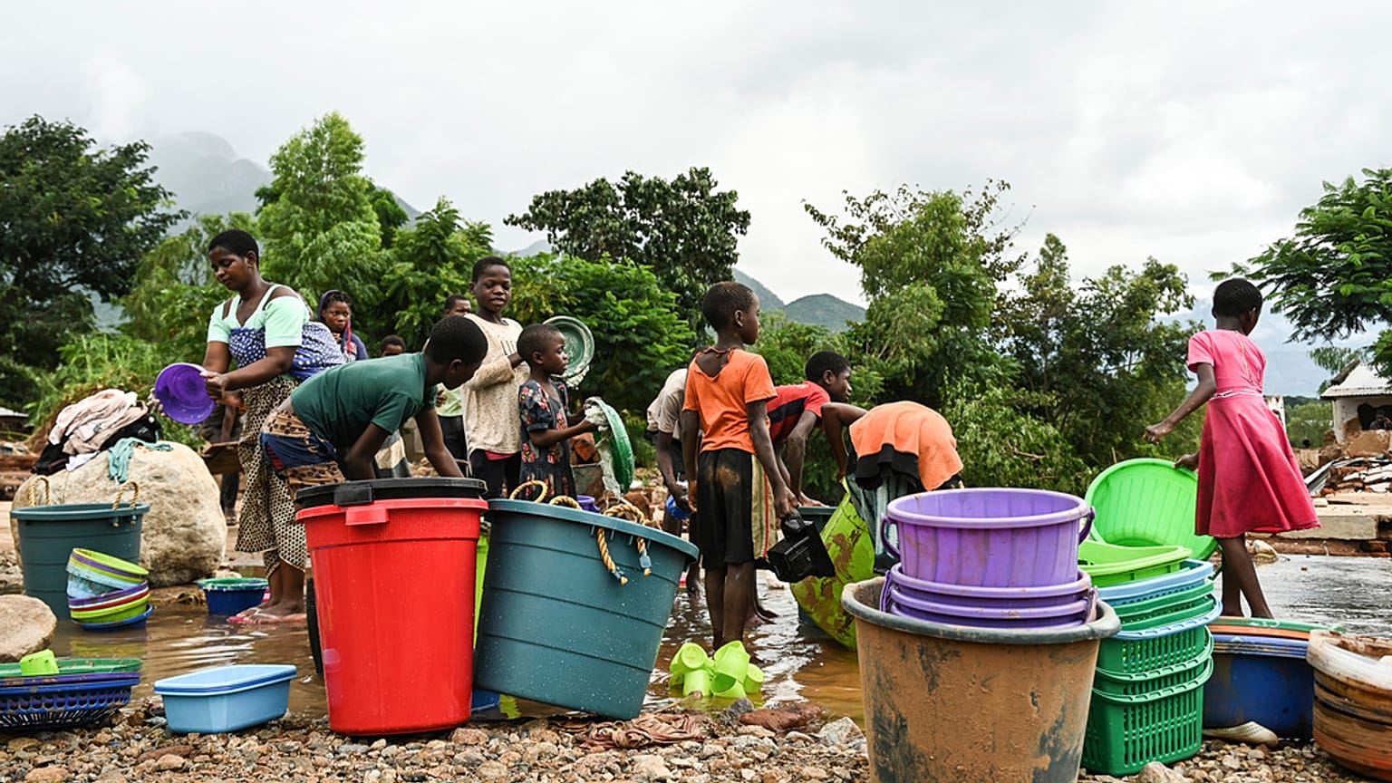 Women and children wash plastic kitchen utensils in a stream in Phalombe, southern Malawi,March 17, 2023.