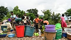 Women and children wash plastic kitchen utensils in a stream in Phalombe, southern Malawi,March 17, 2023.