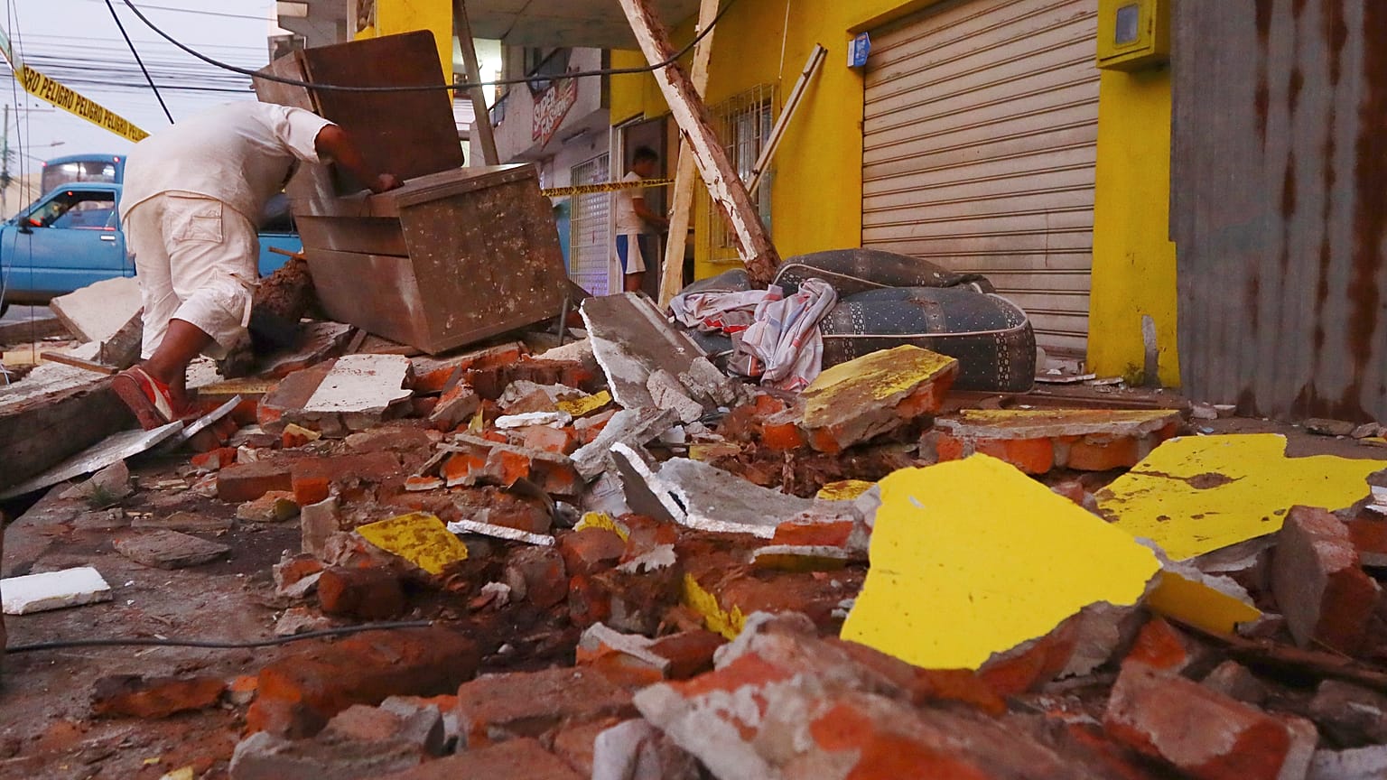 A resident recovers belongings amid the debris of a collapsed home after an earthquake shook Machala, Ecuador, March 18, 2023. 