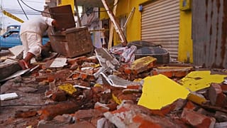 A resident recovers belongings amid the debris of a collapsed home after an earthquake shook Machala, Ecuador, March 18, 2023. 