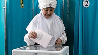 Eine Frau in kasachischer Nationaltracht gibt am Sonntag, den 19. März 2023, in einem Wahllokal in der kasachischen Hauptstadt Astana ihre Stimme ab