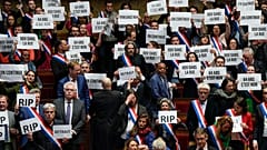 French lawmakers in the National Assembly hold papers reading: "64 years. It is no." 20 March