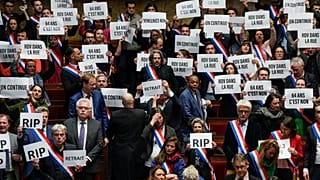 French lawmakers in the National Assembly hold papers reading: "64 years. It is no." 20 March