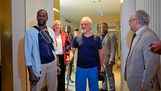 French journalist Olivier Dubois, left, and American aid worker Jeffery Woodke, center, arrive at the VIP lounge at the airport in Niamey, Niger, Monday March 20, 2023.