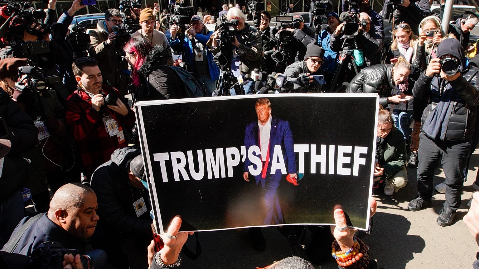 Una mujer sostiene un cartel como parte de una protesta frente al tribunal antes de la acusación anticipada del expresidente Donald Trump, 20 de marzo de 2023, Nueva York