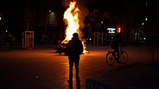 Protester stands in front of a fire in the streets of France.