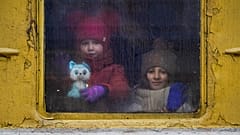 Children look out the window of an unheated Lviv-bound train, in Kyiv, Ukraine, Thursday, March 3, 2022.