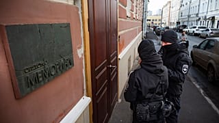 Two Russian police officers stand in front the door of the Memorial office in Moscow, Russia, Tuesday, March 21, 2023