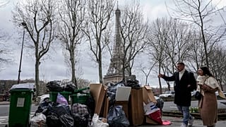 People walk past a pile of garbage near the Eiffel Tower in Paris, March 12, 2023, as strikes continue with uncollected garbage piling higher by the day.
