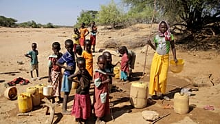 Во время засухи в Кении дети набирают воду в колодце