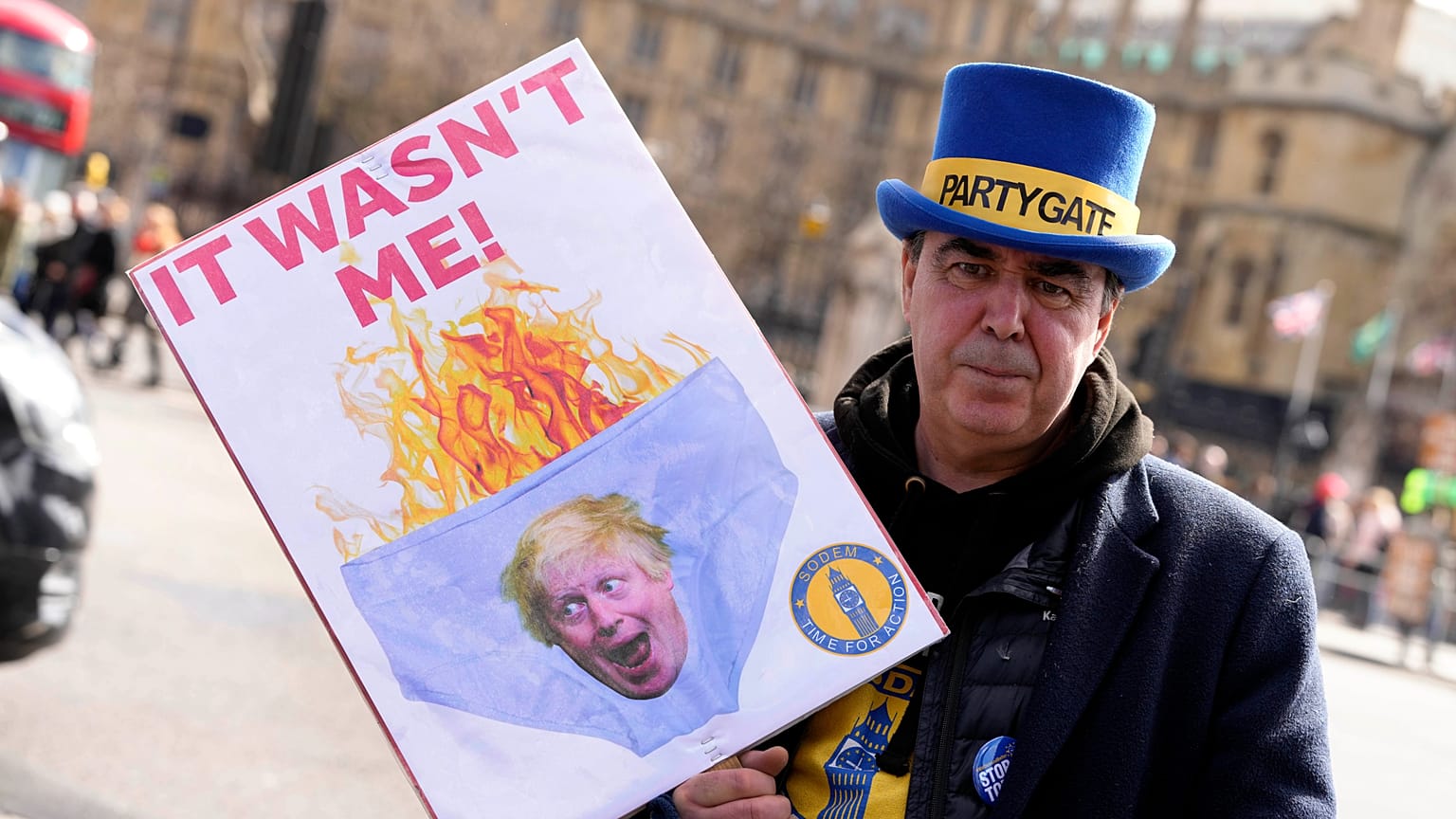 A protester shows a poster near Parliament in London, Wednesday, March 22, 2023. 