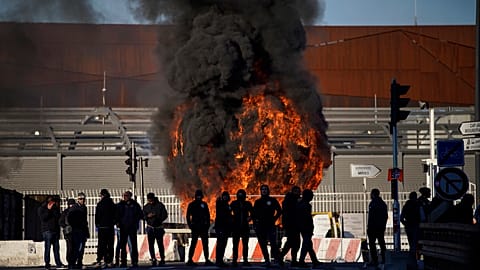 Dock workers stand in front of a burning barricade next the port of Marseille southern France, Wednesday, March 22, 2023.