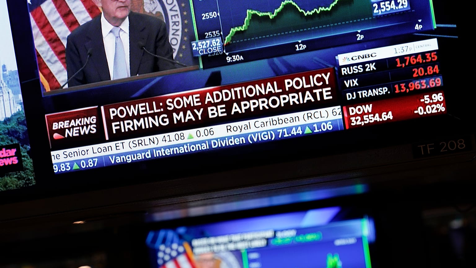 Οι οθόνες στην Wall Street δείχνουν τον κεντρικό τραπεζίτη των ΗΠΑ Τζερόμ Πάουελ κατά την ανακοίνωση της νέας αύξησης