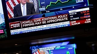 Οι οθόνες στην Wall Street δείχνουν τον κεντρικό τραπεζίτη των ΗΠΑ Τζερόμ Πάουελ κατά την ανακοίνωση της νέας αύξησης
