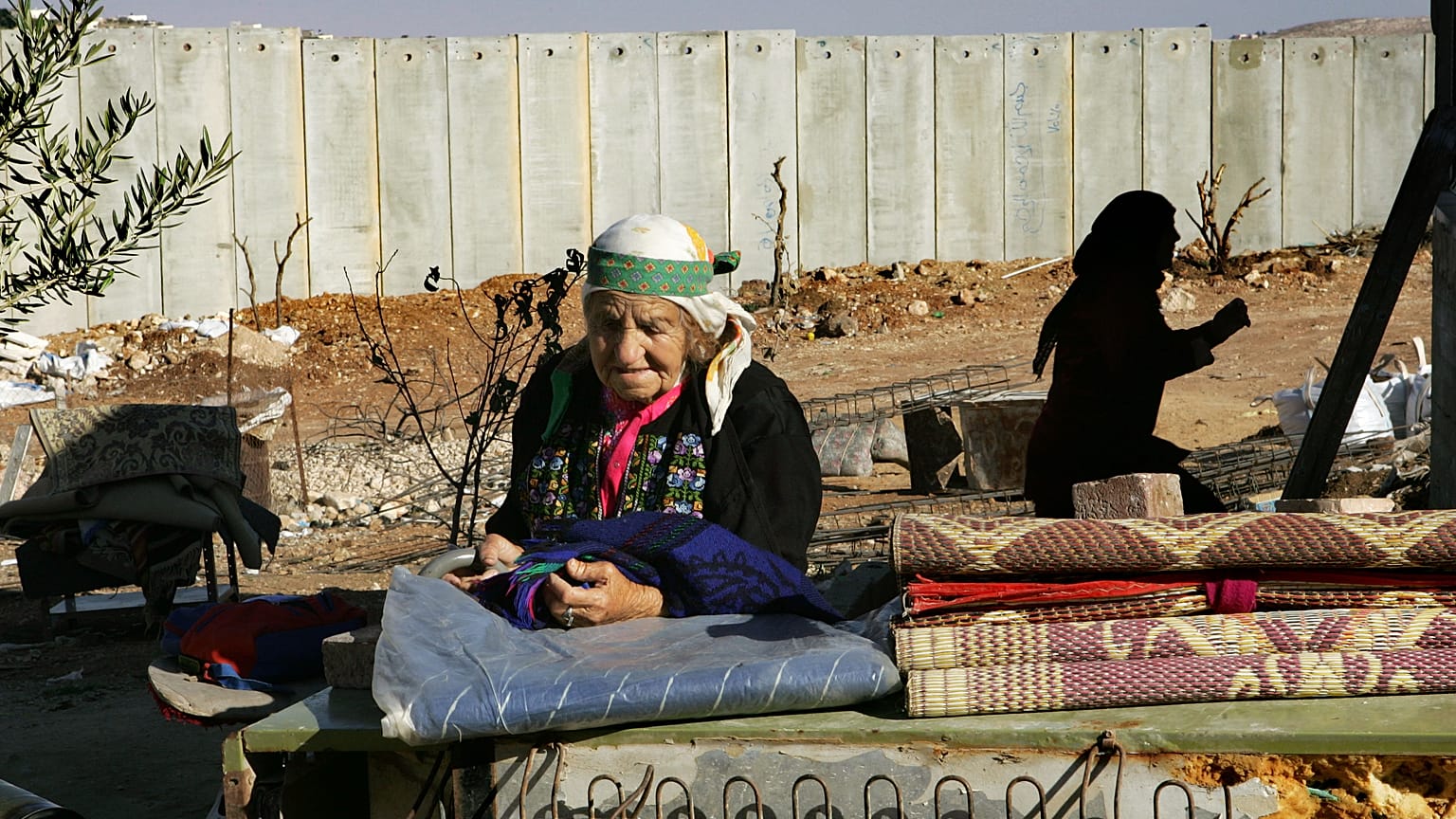  فلسطينية تقف في الفناء الخلفي لمنزلها الواقع بجوار جدار الفصل الإسرائيلي، في قرية حزما بالضفة الغربية