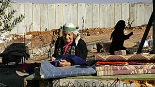  فلسطينية تقف في الفناء الخلفي لمنزلها الواقع بجوار جدار الفصل الإسرائيلي، في قرية حزما بالضفة الغربية