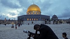 A man observes the moon through a telescope next to the Dome of Rock Mosque at the Al-Aqsa Mosque compound in Jerusalem's Old City, Tuesday, March 21, 2023