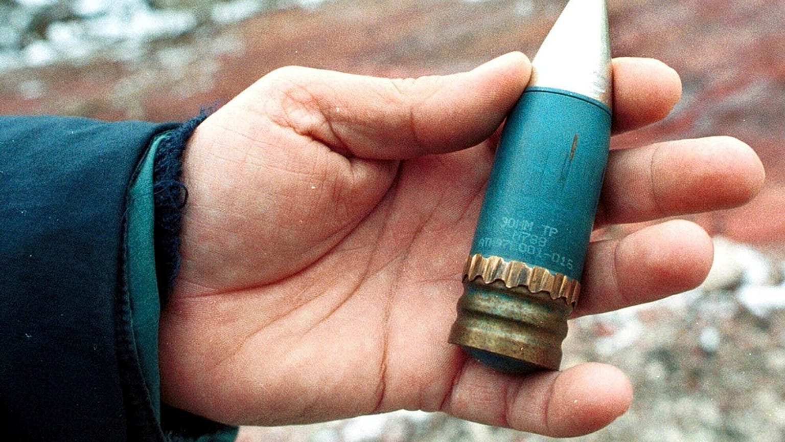 FILE - A member of a radiation team holds a 30mm armour-piercing shell containing depleted uranium, used by NATO during air strikes on Bosnia in 1995.