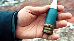 FILE - A member of a radiation team holds a 30mm armour-piercing shell containing depleted uranium, used by NATO during air strikes on Bosnia in 1995.