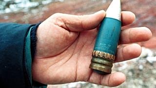 FILE - A member of a radiation team holds a 30mm armour-piercing shell containing depleted uranium, used by NATO during air strikes on Bosnia in 1995.