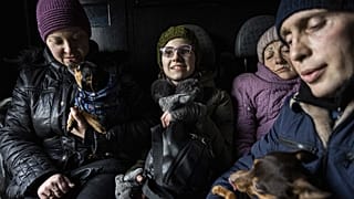 Arina, center, rides inside a car with her family during an evacuation by Ukrainian police, in Avdiivka, Ukraine, March 7, 2023. 