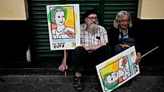People hold signs with the image of Argentina's former first lady María Eva Duarte de Perón, as they rest during a march marking the 47th anniversary of the military coup. 