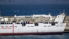 Migrantes a bordo de barco da guarda costeira italiana prestes a desembarcar em Reggio Calabria