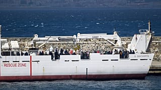 Migrantes a bordo de barco da guarda costeira italiana prestes a desembarcar em Reggio Calabria