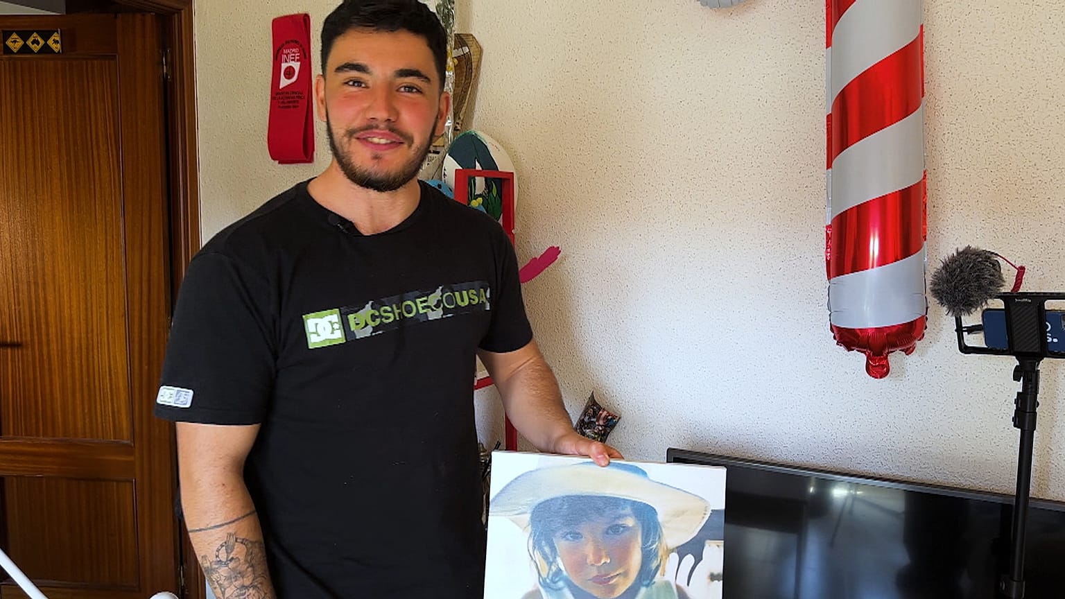 Ezekiel posa com um retrato de quando era criança, enquanto menina.