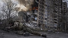 Ukrán rendőrtiszt fedezéket keres egy égő ház előtt Avdijivkában