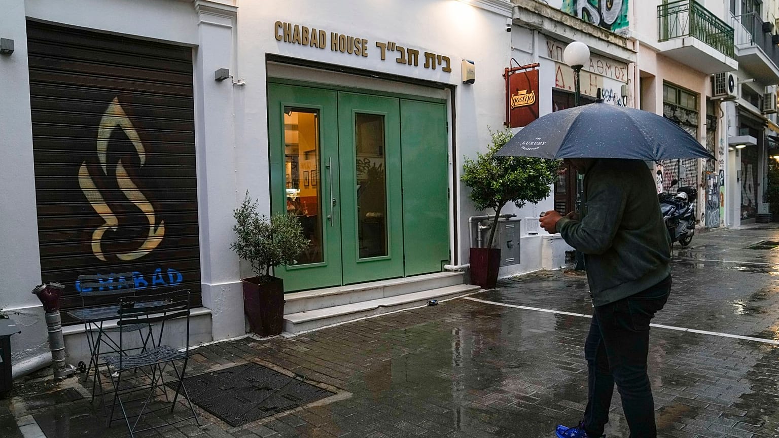 A man holding an umbrella stands in front of a Jewish restaurant that Greek officials believe was one of the targets of a planned terrorist attack, in central Athens, March 28