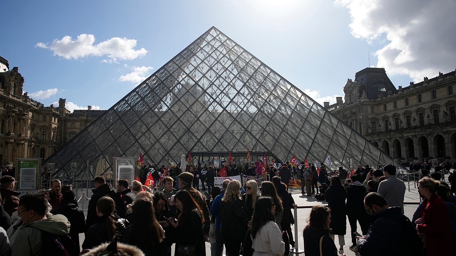 Visitors wait as workers of the culture industry demonstrate outside the Louvre museum.