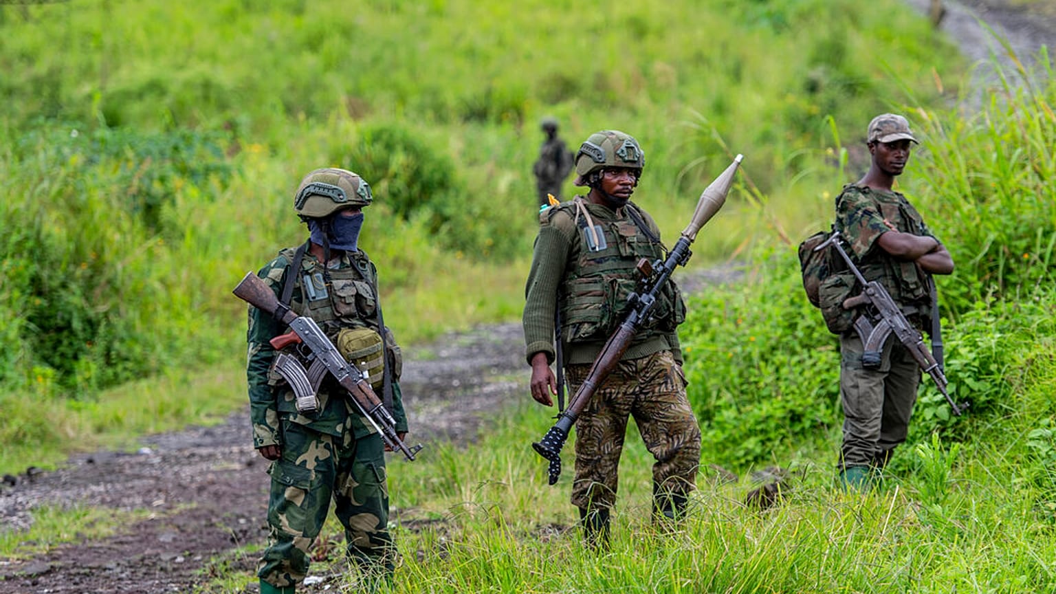 Rebeldes do M23 de pé com as suas armas durante uma cerimónia para assinalar a retirada das suas posições na cidade de Kibumba, no leste da República Democrática do Congo, em D