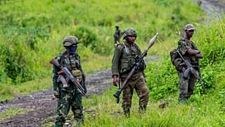 Rebeldes do M23 de pé com as suas armas durante uma cerimónia para assinalar a retirada das suas posições na cidade de Kibumba, no leste da República Democrática do Congo, em D