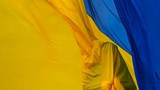 Soldados ucranianos da guarda de honra no haster da bandeira ucraniana em Bucha