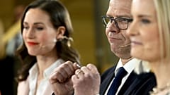 Chair of SDP Sanna Marin, left, and chair of The Finns party Riikka Purra, right, look on as National Coalition Party chair Petteri Orpo cheers at the parliamentary election.