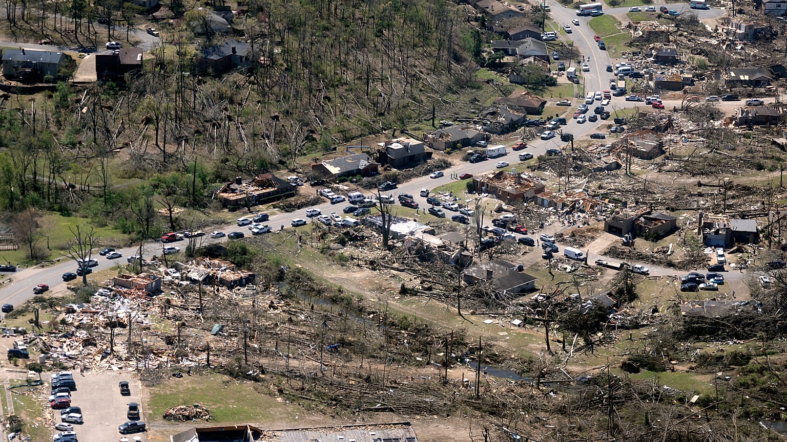 Cars line up along the road as cleanup continues from Friday's tornado damage, 