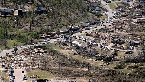 Cars line up along the road as cleanup continues from Friday's tornado damage, 