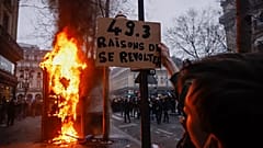 A protester holds a placard that reads, "49.3, reason to rebel", march at the end of a rally in Paris, 23 March 2023.   - 