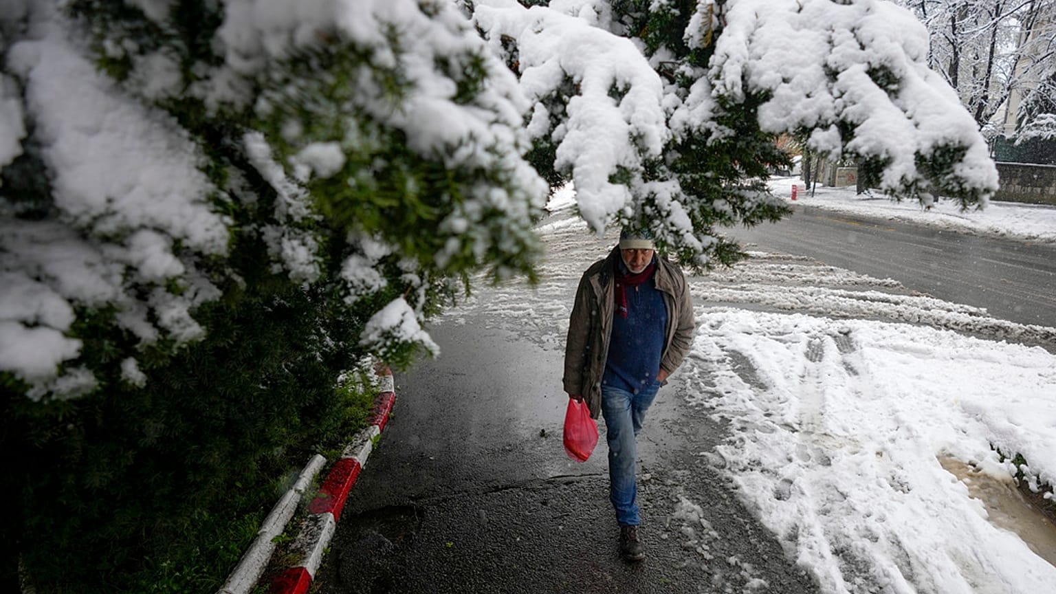 Un homme marche dans une rues enneigée de Belgrade, en Serbie. 4 avril 2023