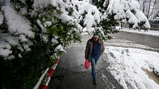 Un homme marche dans une rues enneigée de Belgrade, en Serbie. 4 avril 2023