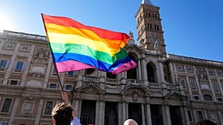 A demonstrator waves the rainbow flag in front of the Basilica of Saint Mary Major during the annual Pride march, in Rome, Saturday, June 26, 2021. 